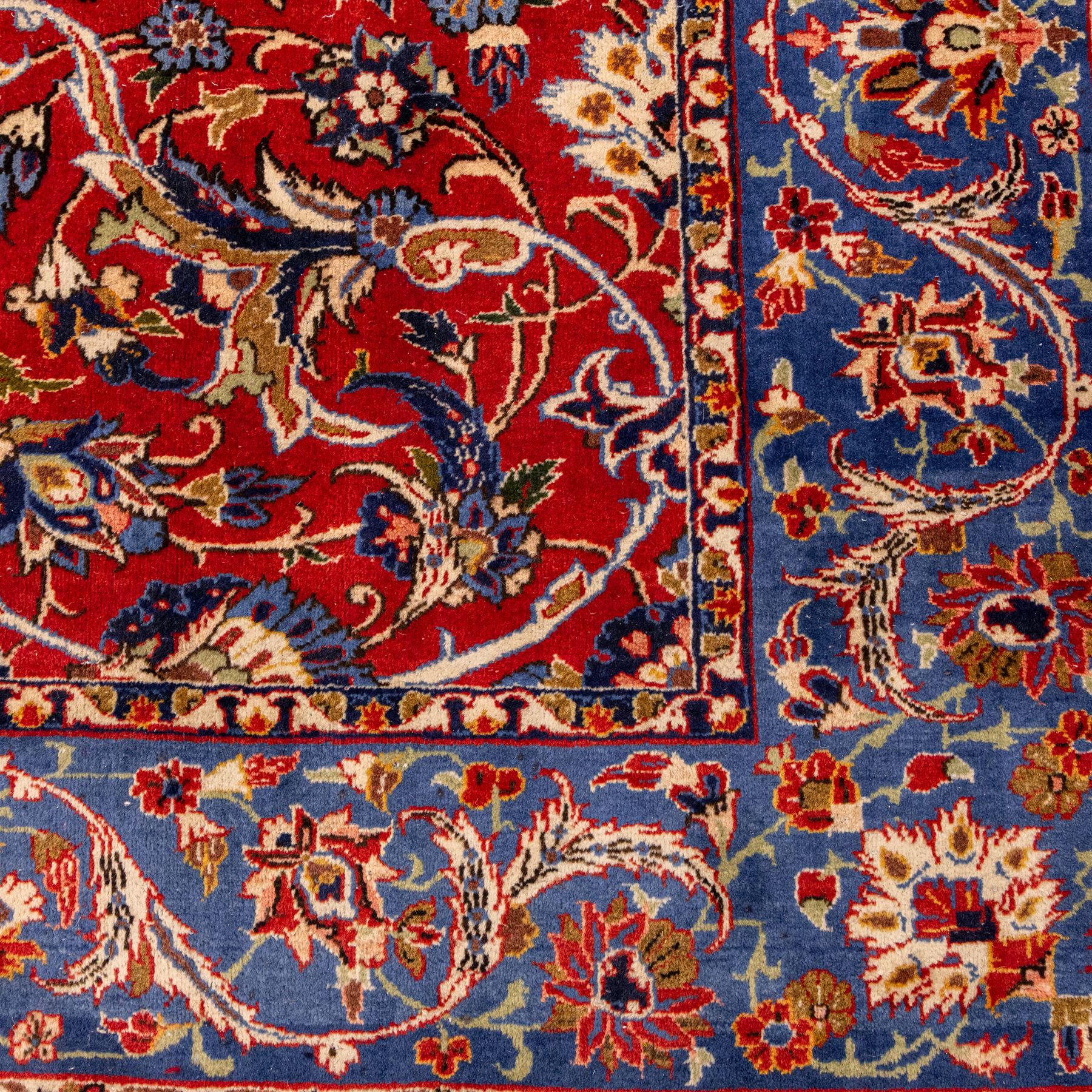 Central Persian Markazi Mahal hand-knotted carpet, terracotta red field, with an all-over scrolling vine design issuing with palmettes, rosettes, and serrated leaves, linked by ivory vinery, deep cobalt blue main border with floral ornamentation, flanked  by multiple guard stripes of repeating geometric motifs, with cotton fringe ends