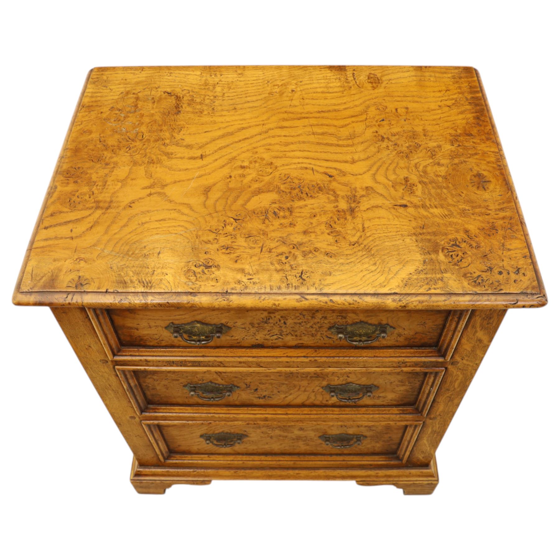 Small 20th century burr oak chest, the figured top over three graduated drawers with moulded fronts and pierced brass handles, on shaped feet