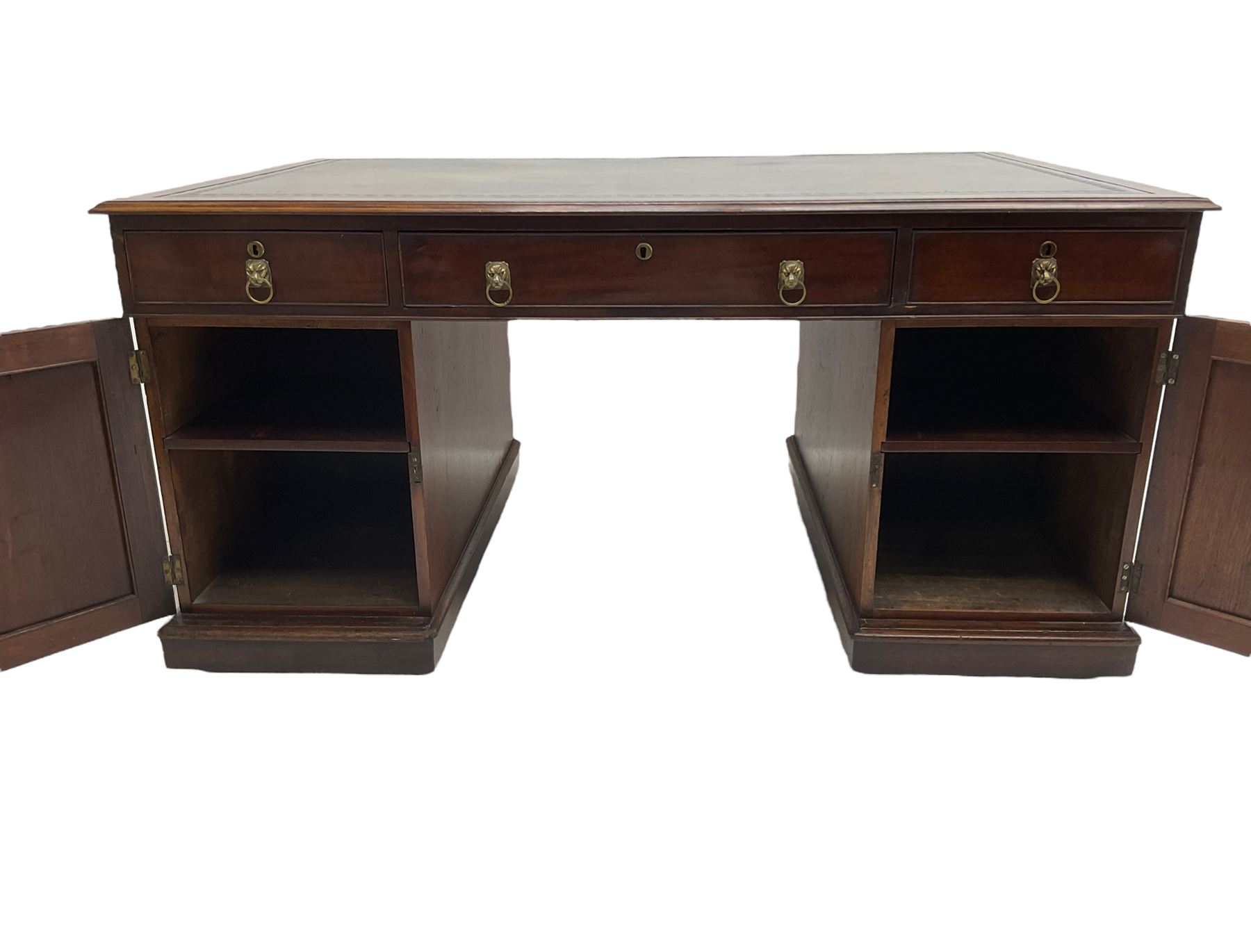 George III mahogany twin pedestal partners desk, rectangular top with moulded edge and an inset green tooled leather writing surface with Greek key design border, fitted with three cock-beaded frieze drawers to each side, each pedestal with three graduating drawers with an opposing panelled cupboard enclosing a single shelf, the facias fitted with brass lion mask plates with ring handles, the lower moulded edge over a plinth base and castors, London furniture dealers label to interior of drawer inscribed 'J. Webb, Office Furniture 323, Gray's Inn Road, King's Cross'  H75cm  W153cm  D97cm