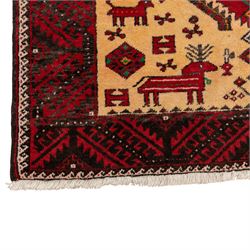 North East Persian Meshed Baluch rug, the ivory field decorated with two stepped diamond medallions and angular red motifs, interspersed with stylised horned animals, birds, flowerheads and geometric devices, enclosed by a dark brown border of repeating red serrated leaves and narrow ivory guard bands