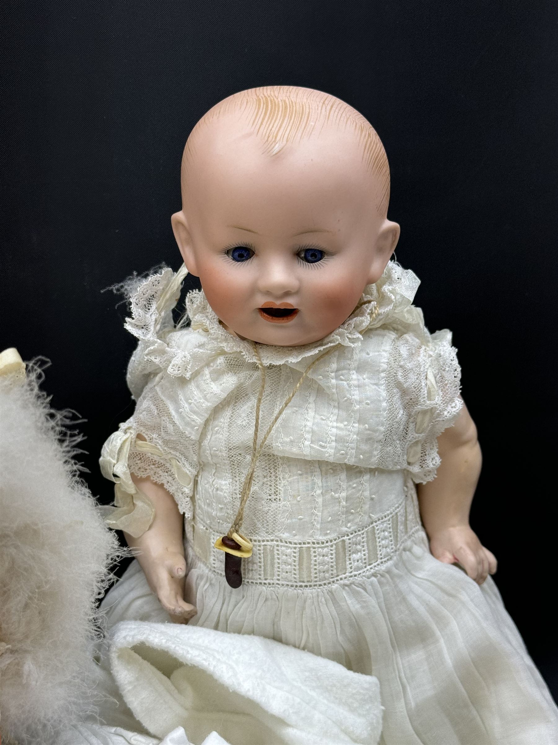 Two German bisque head dolls, to include a Franz Schmidt example with blue glass eyes and an Armand Marseille 590 example with applied hair, together with a Schoenau & Hoffmeister bisque doll's head, pair of doll's hands and a collection of clothing