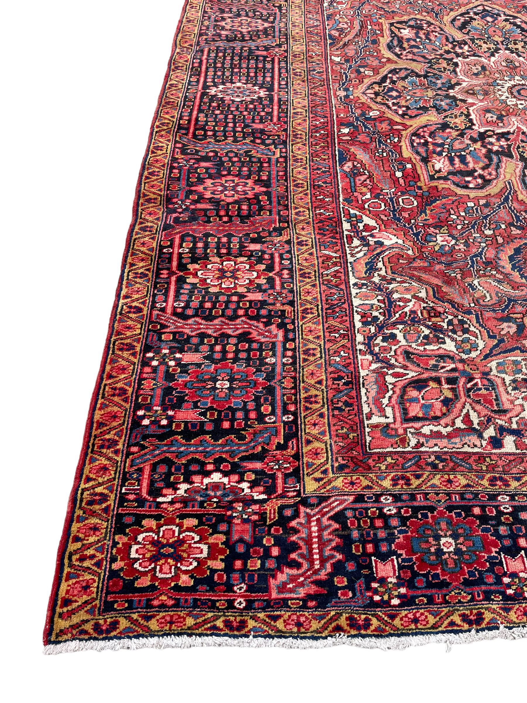 Antique Persian coral ground carpet, the large central floral pole medallion with extending foliate designs, the thick guarded indigo border with repeating flower heads and circles
