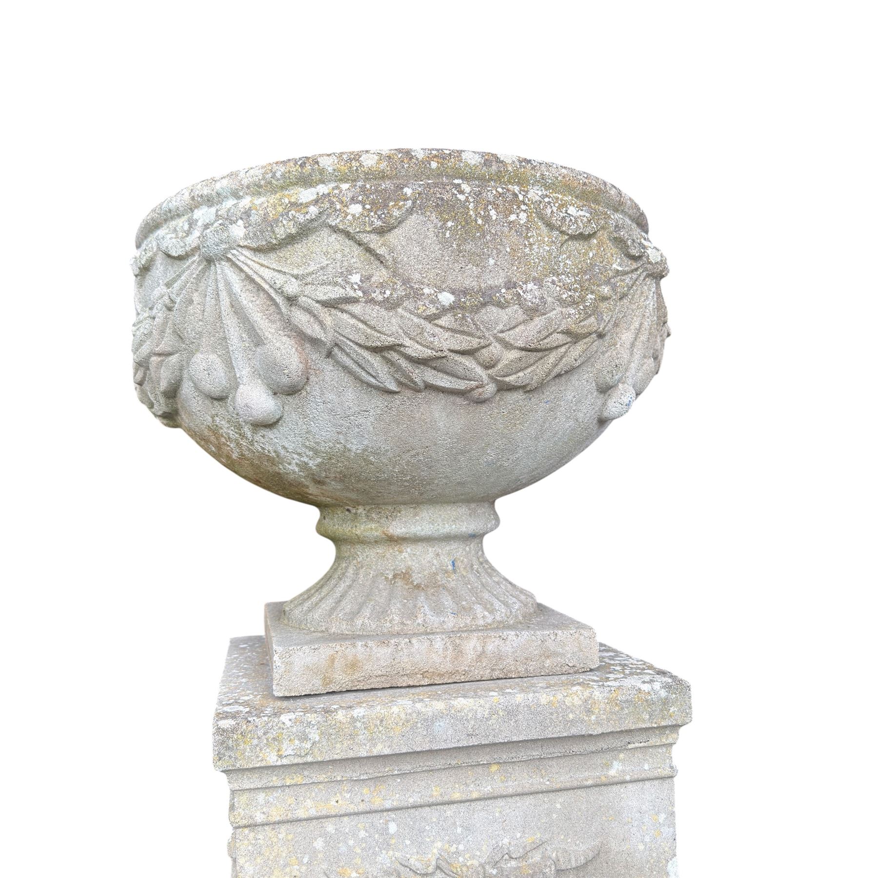 Pair of quality Neoclassical design Haddonstone cast stone garden urns, the globular  body decorated with relief foliate festoons and fruiting motifs, over a fluted socle, the rectangular pedestals with relief foliate wreaths and ribbon garlands