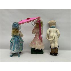 Anna Meszaros Hungary - three hand made needlework figurines - young girl wearing a floral sun-dress and hat, standing on a grassy base holding a pink parasol H33cm; anthropomorphic cat wearing boots and a blue bow-tie H35cm; and young girl wearing a blue/green/white floral dress and lace bonnet, standing holding a floral posy H28cm (3)  Auctioneer's Note: Anna Meszaros came to England from her native Hungary in 1959 to marry an English businessman she met while demonstrating her art at the 1958 Brussels Exhibition. Shortly before she left for England she was awarded the title of Folk Artist Master by the Hungarian Government. Anna was a gifted painter of mainly portraits and sculptress before starting to make her figurines which are completely hand made and unique, each with a character and expression of its own. The hands, feet and face are sculptured by layering the material and pulling the features into place with needle and thread. She died in Hull in 1998.