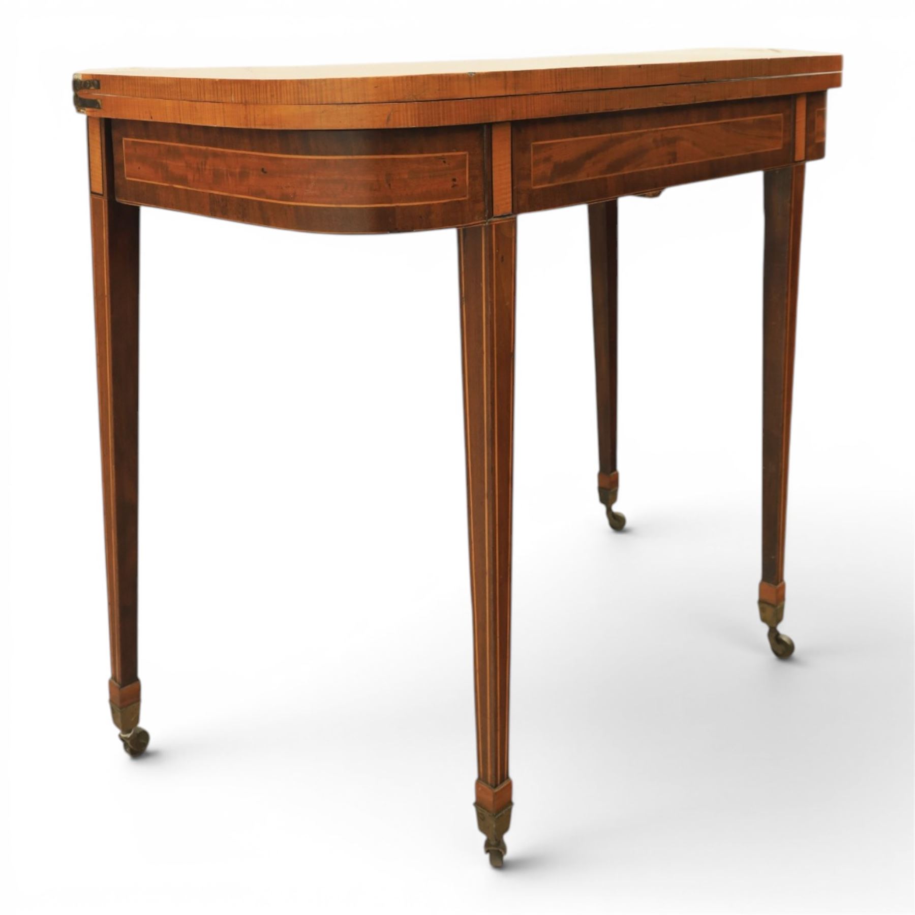 Regency mahogany fold-over tea table, rounded rectangular top with gateleg action, inlaid and crossbanded frieze, raised on squared tapering supports on brass castors