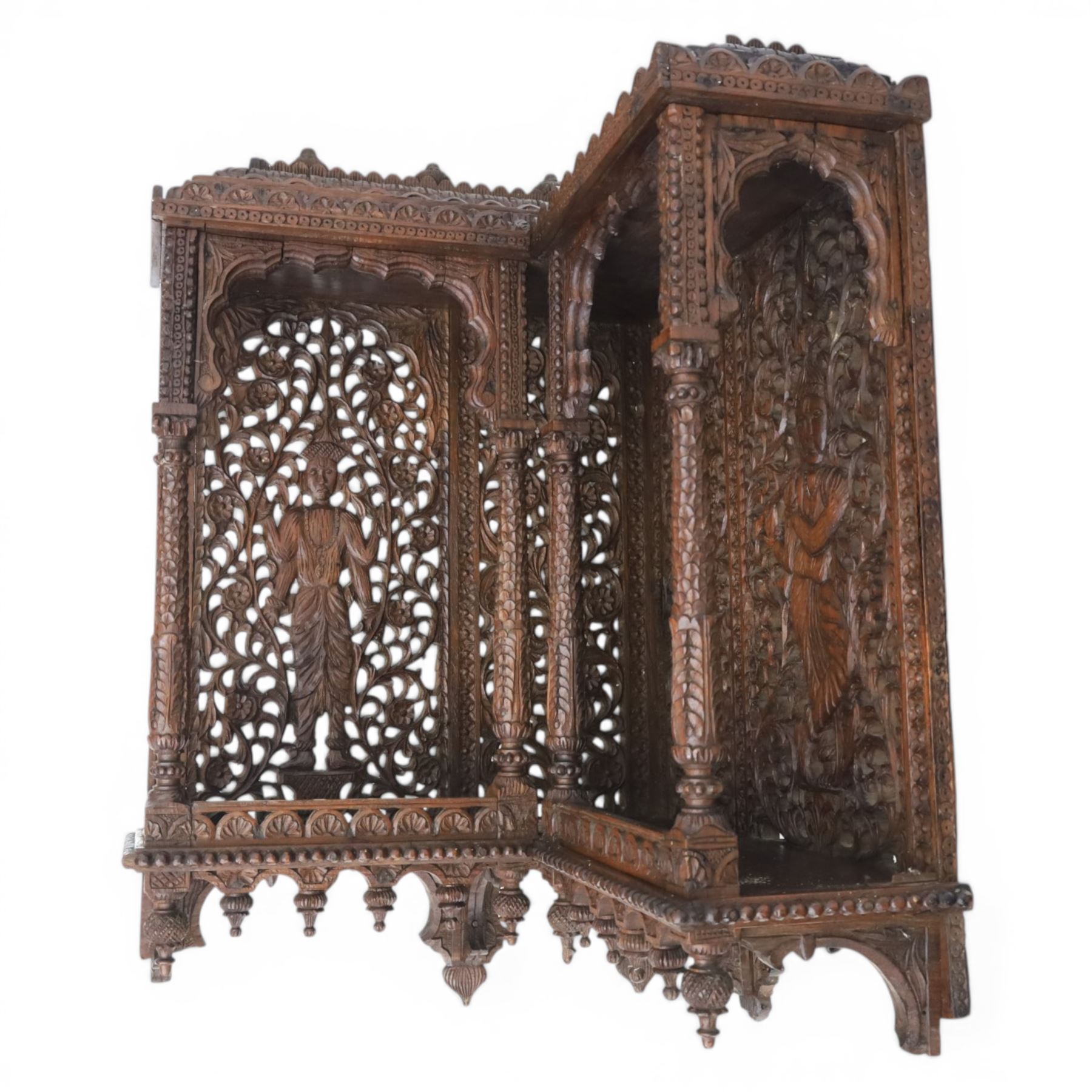 20th century Indian carved hardwood corner shelf, the tiered pagoda form with pierced and carved foliate panels centred by figural carving, supported by turned and carved columns, with shaped brackets and pendant finials