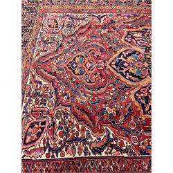 Antique Persian coral ground carpet, the large central floral pole medallion with extending foliate designs, the thick guarded indigo border with repeating flower heads and circles