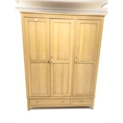 Light oak triple wardrobe, projecting cornice, three doors enclosing fitted interior above one long and one short drawer, stile supports 