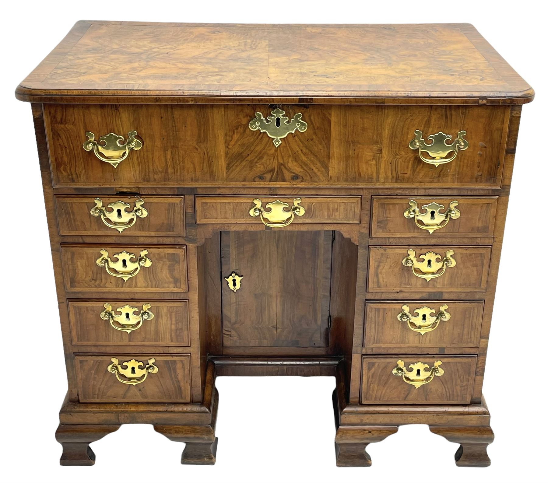 Early 18th century Queen Anne figured walnut kneehole desk with secretaire drawer, moulded and book matched top with walnut band, the top drawer with fall front enclosing small drawers and pigeon holes, fitted with nine drawers and central recessed cupboard, on ogee bracket feet