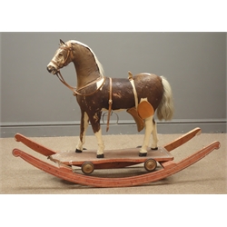  19th/ early 20th century pull-along horse, pony-skin covered wooden frame with glass eyes and leather bridle on rectangular stained pine base with four cast metal wheels, later converted to a rocking horse, H85cm x L115cm   