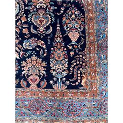 Northeastern Persian Meshed carpet, the deep navy field with a symmetrical floral arrangement of stylised flowerheads, palmettes and scrolling vines issuing from a central urn, enclosed by broad rust and blue borders of floral arabesques and lotus forms, from the region of Meshed