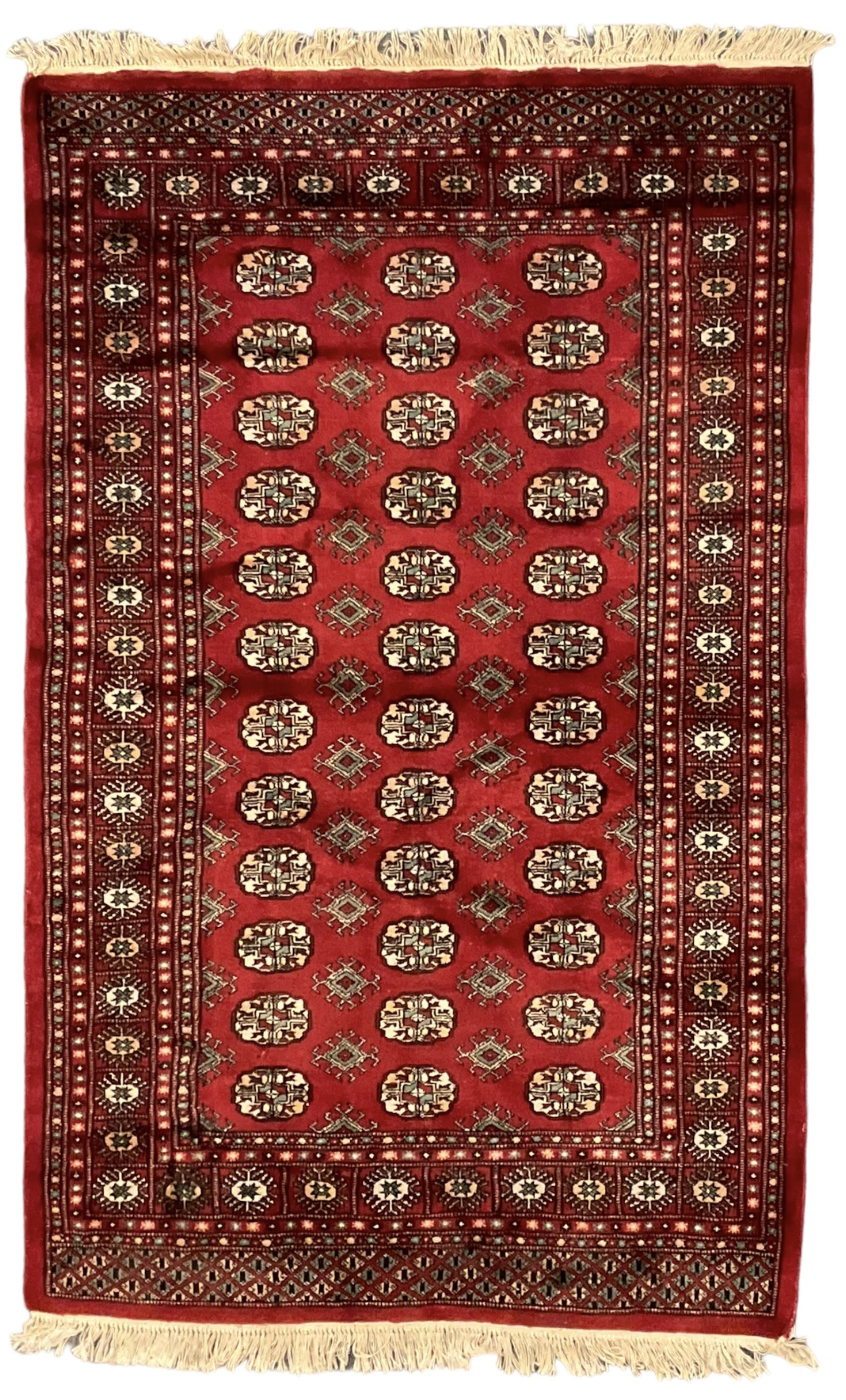 Persian Bokhara crimson ground rug, the field decorated with repeating Gul motifs and lozenges, the multi-band border with stylised plant motifs with black outlines