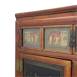 Late 19th century Chinese Qing dynasty red and black lacquered wood cabinet,  Fujianese province, upper cupboard enclosed by two doors with relief carved and gilt panels depicting figures behind glass, the large cupboard enclosed by two panelled doors carved with trailing foliate branches and birds, inscribed with Chinese characters, to the left ‘The red mountains are in the shape of Phoenixes and appear auspicious’ and to the right, ‘Wealth and honour are given by flowers and I hear the sound of the phoenix', fitted with two drawers, on square supports with carved brackets 