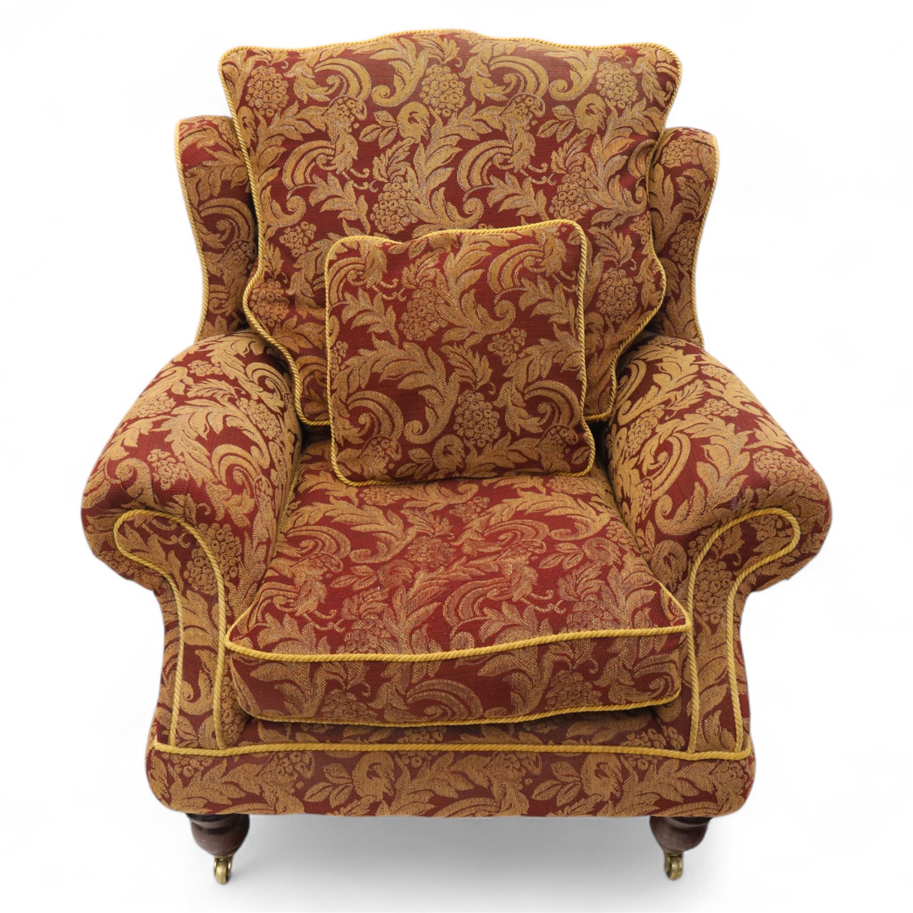 Duresta – pair of armchairs, upholstered in red and gold damask fabric with piped edges, scroll arms and loose feather-filled cushions, raised on turned wooden feet with brass castors