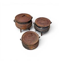 Three South African cast iron graduating cooking pots with lids and handles. Size shown for the largest