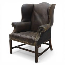 Georgian style leather wing armchair, shaped high back with outscrolled wings above padded arms and deep buttoned seat, close-nailed throughout, raised on square supports united by H-stretcher