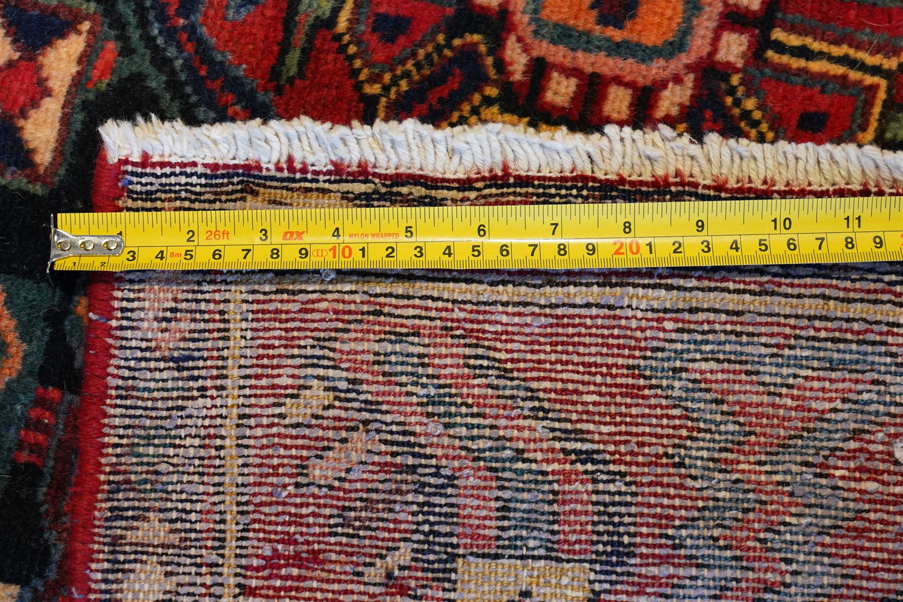 North West Persian Heriz hand-knotted rug, madder red field with an all-over lattice of stepped lozenge medallions enclosing stylized geometric floral motifs and ivory reserve panels, framed by angular vinery and motif borders, main border with with stylized rosettes and geometric devices, flanked by narrow guard stripes,, cotton fringe ends 