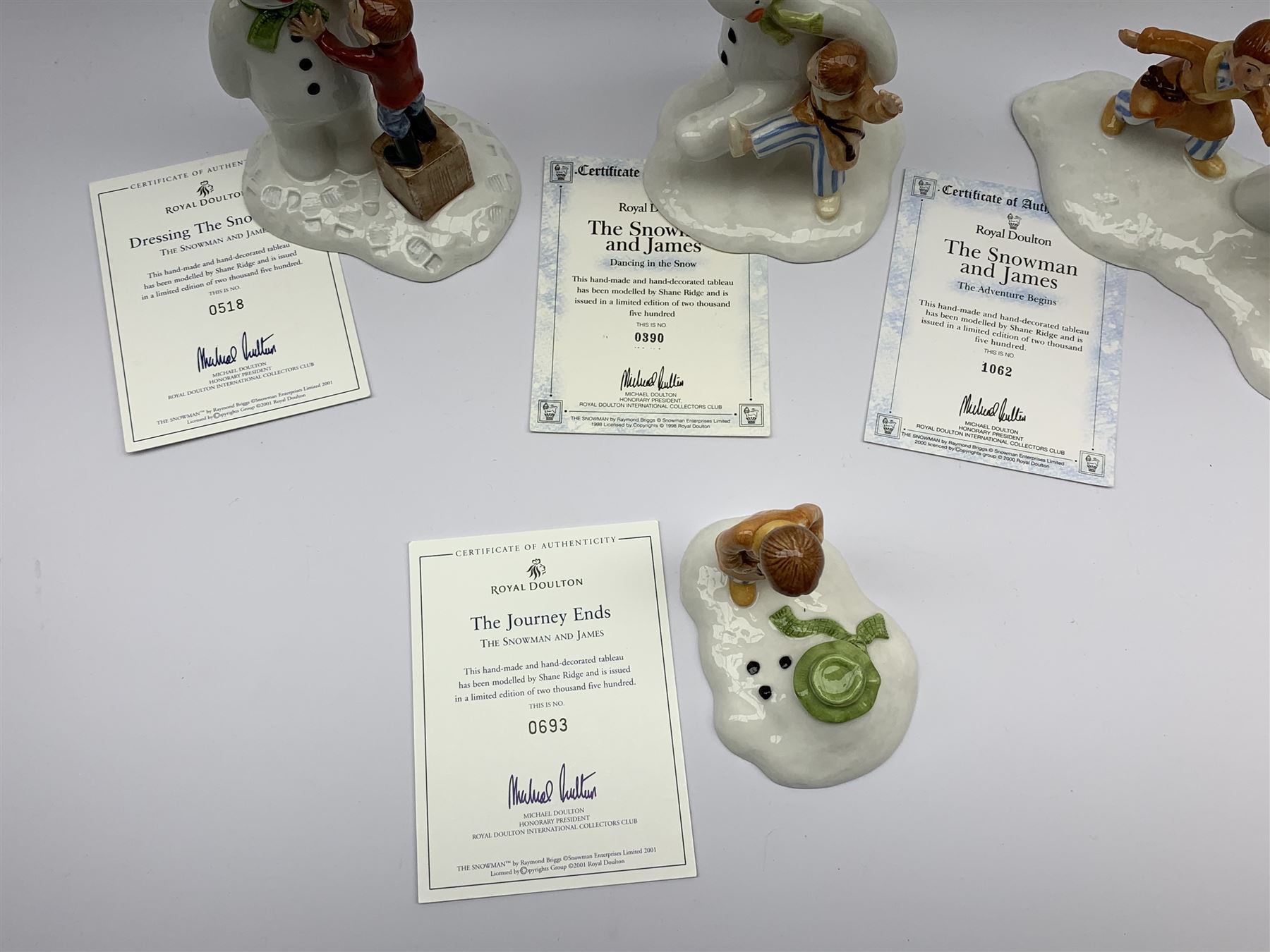 Four limited edition Royal Doulton The Snowman figures, comprising The Snowman and James dancing in the snow, 390/2,500, The Snowman and James Dressing the Snowman, 518/2,500, The Snowman and James The Adventure Begins, 1062/2,500, and The Snowman and James The Journey Ends, 693/2,500, each with accompanying certificate. 