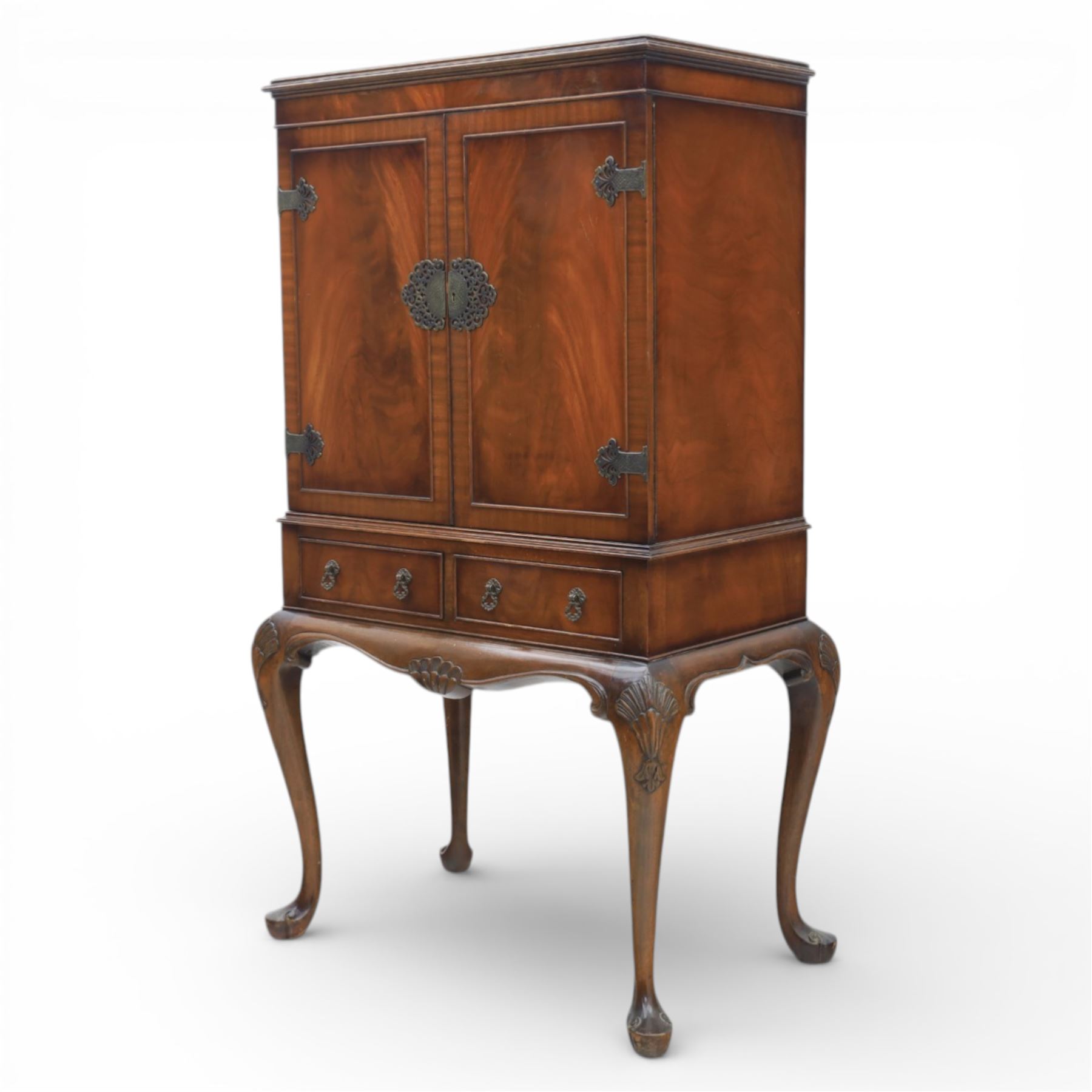 20th century Queen Anne style mahogany cocktail cabinet, moulded cornice above a pair of fielded panel doors with decorative strap hinges and central escutcheon, opening to a mirrored interior fitted with tiered shelves with brass gallery rails, pull-out glass inset mixing slide above three short drawers, shaped apron on cabriole supports with carved shell knees terminating in pad feet