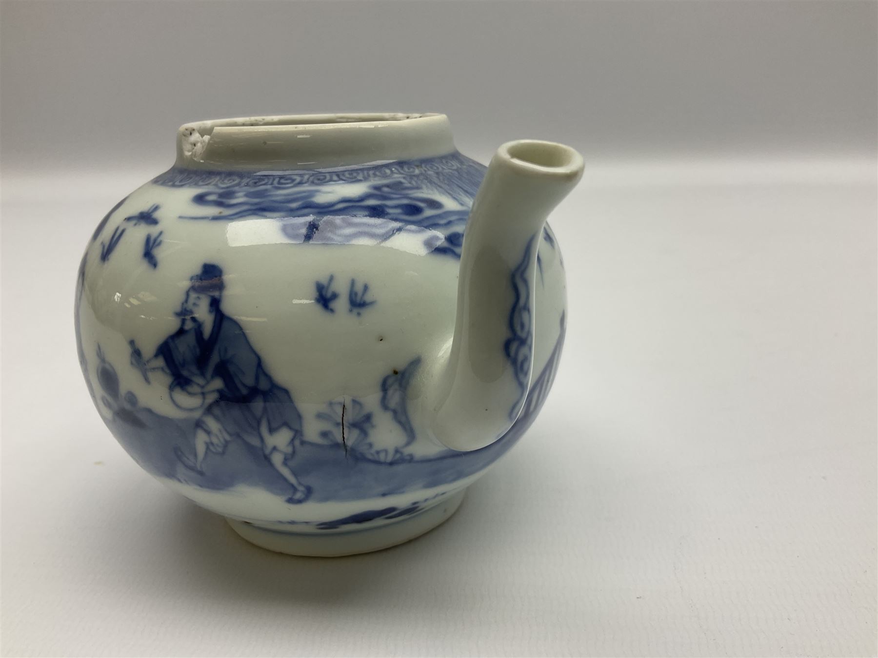 Two late 18th/early 19th century Chinese export teapots, the largest example of globular form with curved handle and straight spout, decorated in the Mandarin style with figural scenes surrounded by red scale reserves, H13.5cm, the second smaller example decorated in underglaze blue with two musicians in a landscape set with willow tree and fence, H10.5cm

