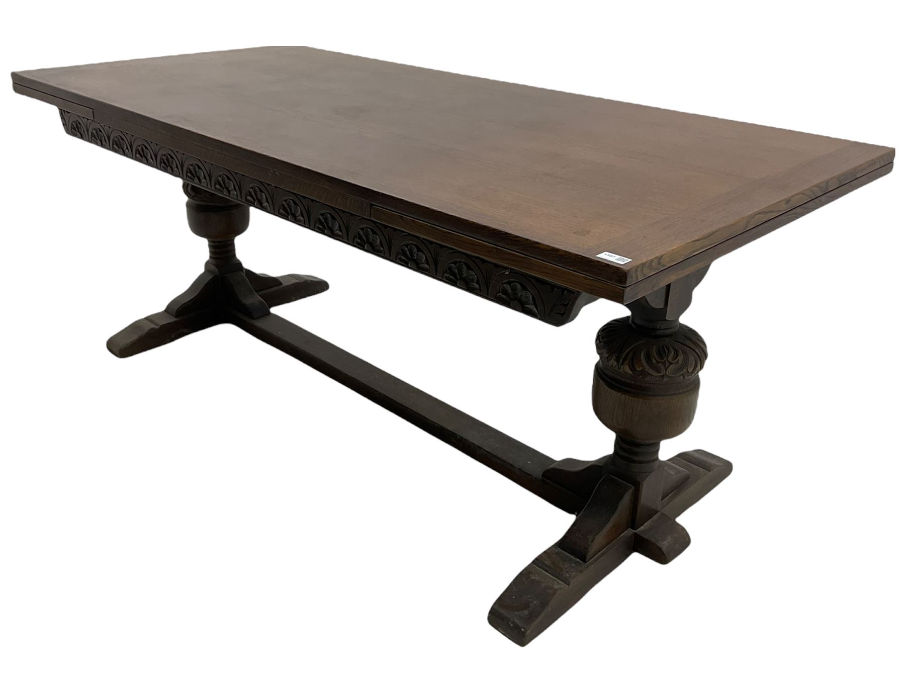 20th century oak drawer leaf extending dining table, two foliage carved baluster supports on sledge feet joined by floor stretcher 
