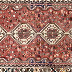 South West Persian Abadeh hand-knotted runner, madder red field decorated with a vertical sequence of stepped lozenge medallions, each enclosing stylized geometric motifs and angular devices, surrounding field filled with tribal symbols and abstract forms, enclosed within a narrow main border and flanked by multiple guard stripes, with fringe ends 