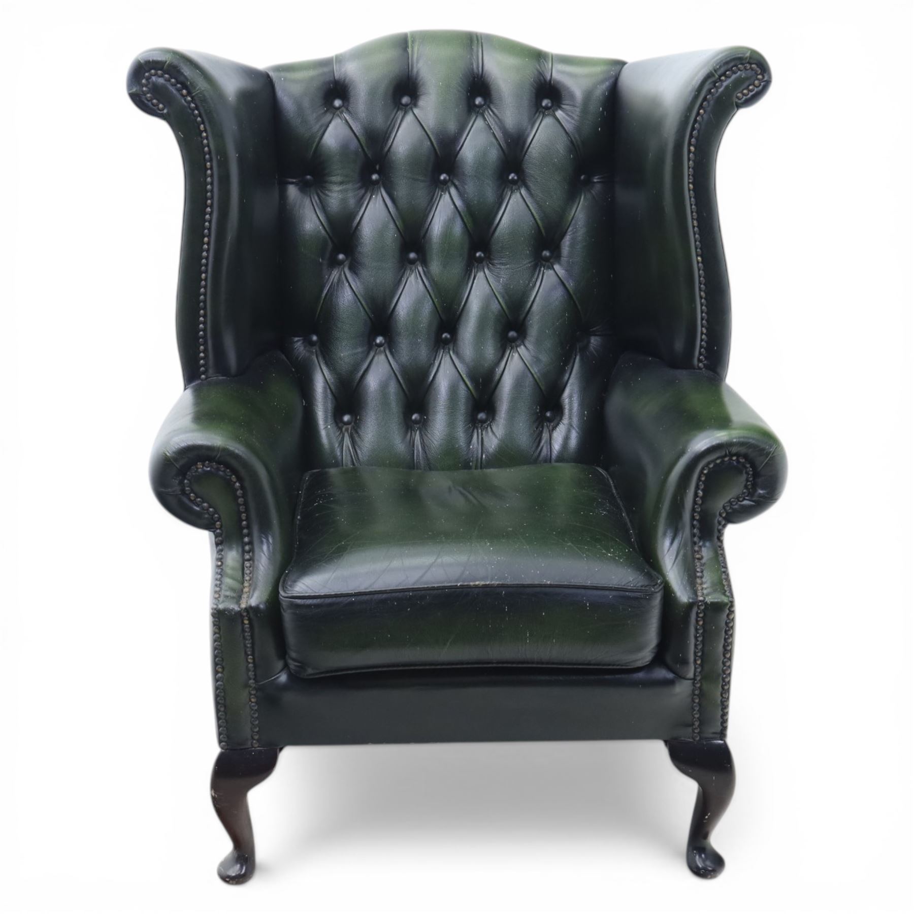 Late 20th century green leather chesterfield style wingback armchair, with deep buttoned back, scrolled wings and arms with studded borders, loose seat cushion, raised on cabriole legs