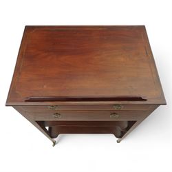 George III mahogany and boxwood-strung drawing table, the rectangular sloping reading surface with rest and oak stay, above a blind drawer and a drawer fitted with brass ring handles, side with pull-out candleholder and inkwell compartment, raised on square-section tapered legs with brass box castors united by two galleried under tiers