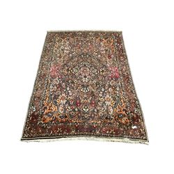 Persian Meshed red ground carpet, the cusped field profusely decorated with stylised flower head and plant motifs, the guarded border with scrolling foliate design