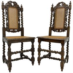 Pair of Victorian Gothic Revival carved oak chairs, decorated with pierced and carved vines with spiral turned uprights, cane seat and back, raised on barley-twist supports