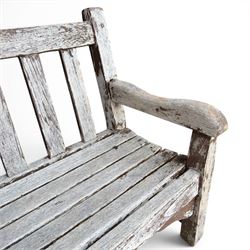 Teak garden bench with slatted back and seat on square supports in weathered which finish 