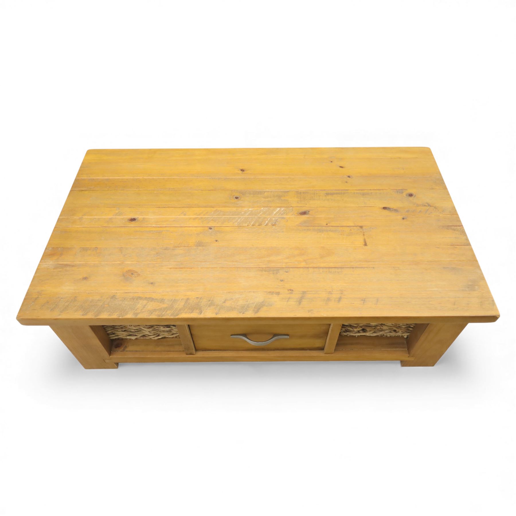 Contemporary pine coffee table, rectangular planked top with moulded edge, fitted with a central drawer to either side with brushed metal handle, flanked by two open compartments housing wicker basket drawers, plain sides, raised on square block feet