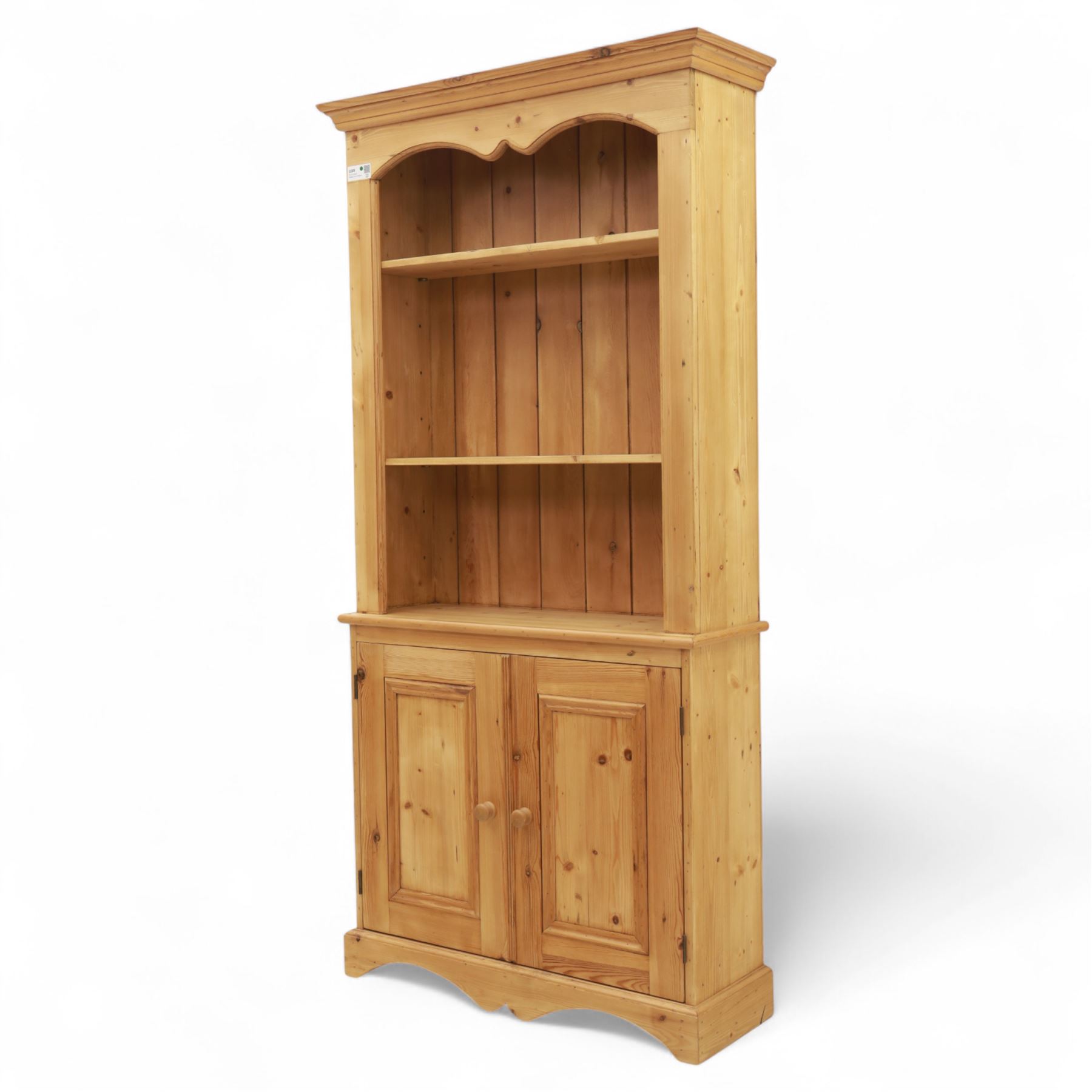 Contemporary pine kitchen dresser, moulded cornice over open plate rack with shaped frieze and two fixed shelves, enclosed lower section with panelled twin doors and shaped plinth base