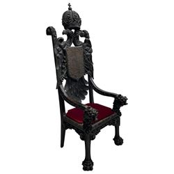 Grand mid-to-late 19th century heavily carved beech framed throne chair, the crown pediment carved with flower heads and cross finial, scroll and acanthus carved upright supports with twin perching griffin back enclosing etched leather work heraldic shield with castle and lion motifs over splayed feathers, flower head carved down sweeping arms with grotesque carved terminals, the seat rails carved with further flower heads on moulded supports with oversized ball and claw carved feet

Provenance: A very similar chair was used in the filming of Stanley Kubrick's 'Eyes Wide Shut' (1999)
