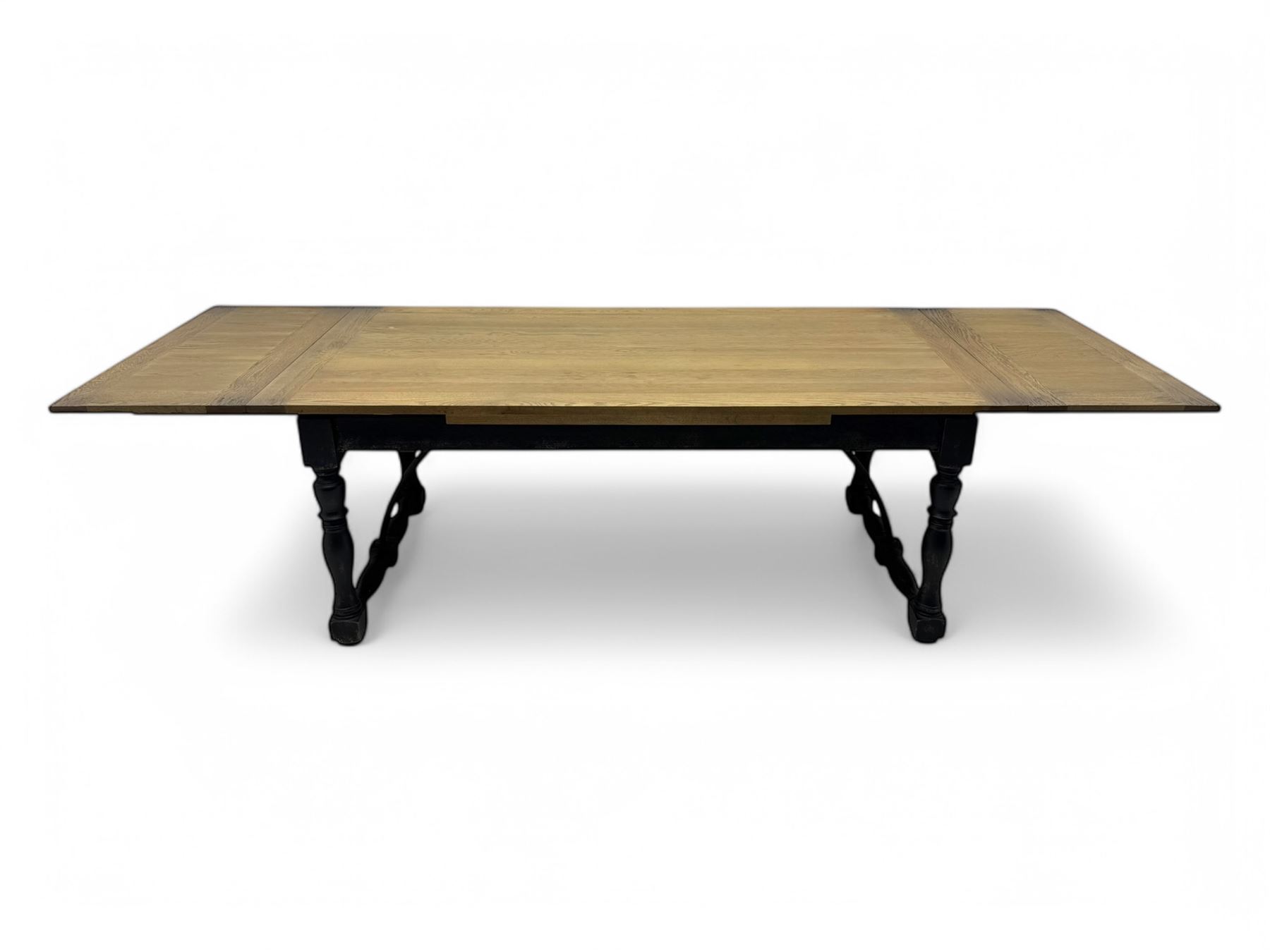 Barker & Stonehouse - large oak extending draw-leaf dining table, rectangular plank top over a black painted base, turned supports joined by shaped stretchers, extending at each end with pull-out leaves