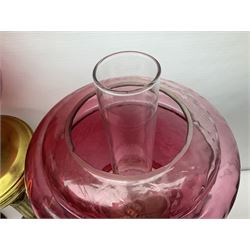 Victorian cast brass oil lamp, with fluted pink glass shade, together with two smaller brass oil lamps with pink shades and reservoirs and a pair of oil lamps, the bases modelled as putti, with pink glass reservoir  and frosted shades, tallest H70cm