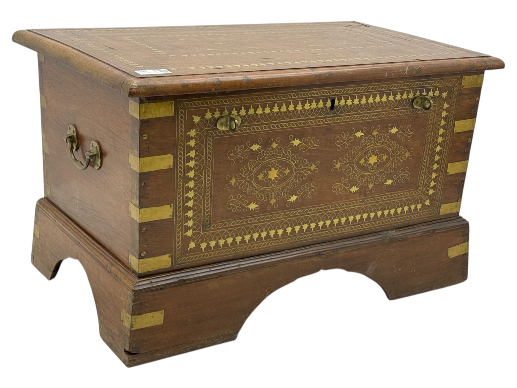 Zanzibar chest, early 20th century, of hardwood construction with brass inlaid foliate and geometric decoration to the lid, fitted interior of multiple carved compartments, with brass strapwork, side handles, and shaped bracket feet