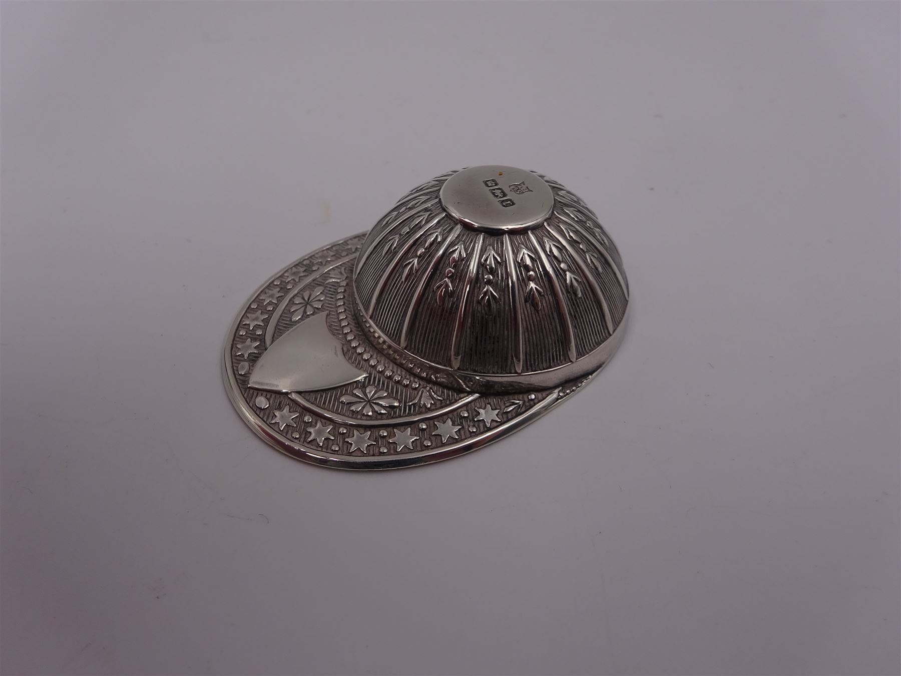 Edwardian silver caddy spoon, in the form of a jockeys cap, with embossed decoration and blank shield shaped cartouche, hallmarked Thomas Bradbury & Sons Ltd, Sheffield 1909, L5.3cm