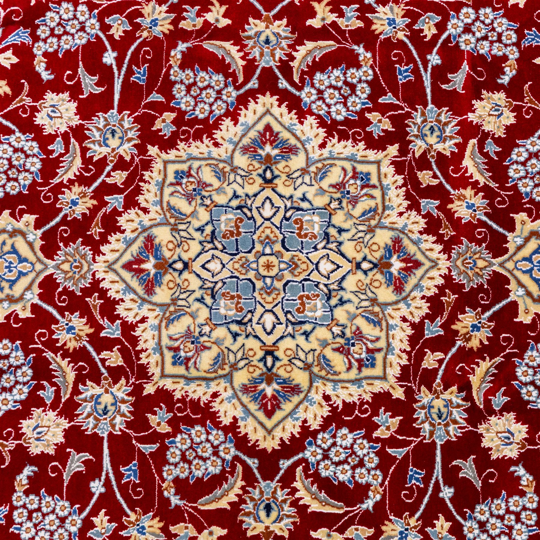 Central Persian Nain hand-knotted rug, crimson field, with central ornate ivory medallion with scrolling arabesques and flowering vine ornaments within a dense floral lattice framed by pale blue corner spandrels and enclosed with an ivory border of scrolling vine and palmette decoration between multiple guard stripes, with cotton fringe ends 
