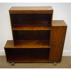  Art Deco oak bookcase, three staggered shelves flanked by single cupboard, on sledge feet (W91cm, H93cm, D24cm) and an oak hallstand, raised shaped back, single drawer, square supports joined by solid undertier with metal umbrella stand tray (W77cm, H87cm, D83cm)  