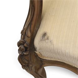 Late Victorian walnut open armchair, the carved shaped cresting rail centred by scrolls and foliage above a padded serpentine back and overstuffed seat upholstered in cream striped fabric, with padded scroll arms on open carved supports, raised on cabriole supports with carved knees and ceramic castors