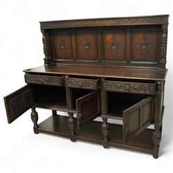 Early 20th century carved oak sideboard Jacobean style with panel back on cup and cover legs, the top section with carved panels and reeded moulding, three deep frieze drawers over triple panelled cupboard doors, raised on carved baluster legs joined by lower shelf