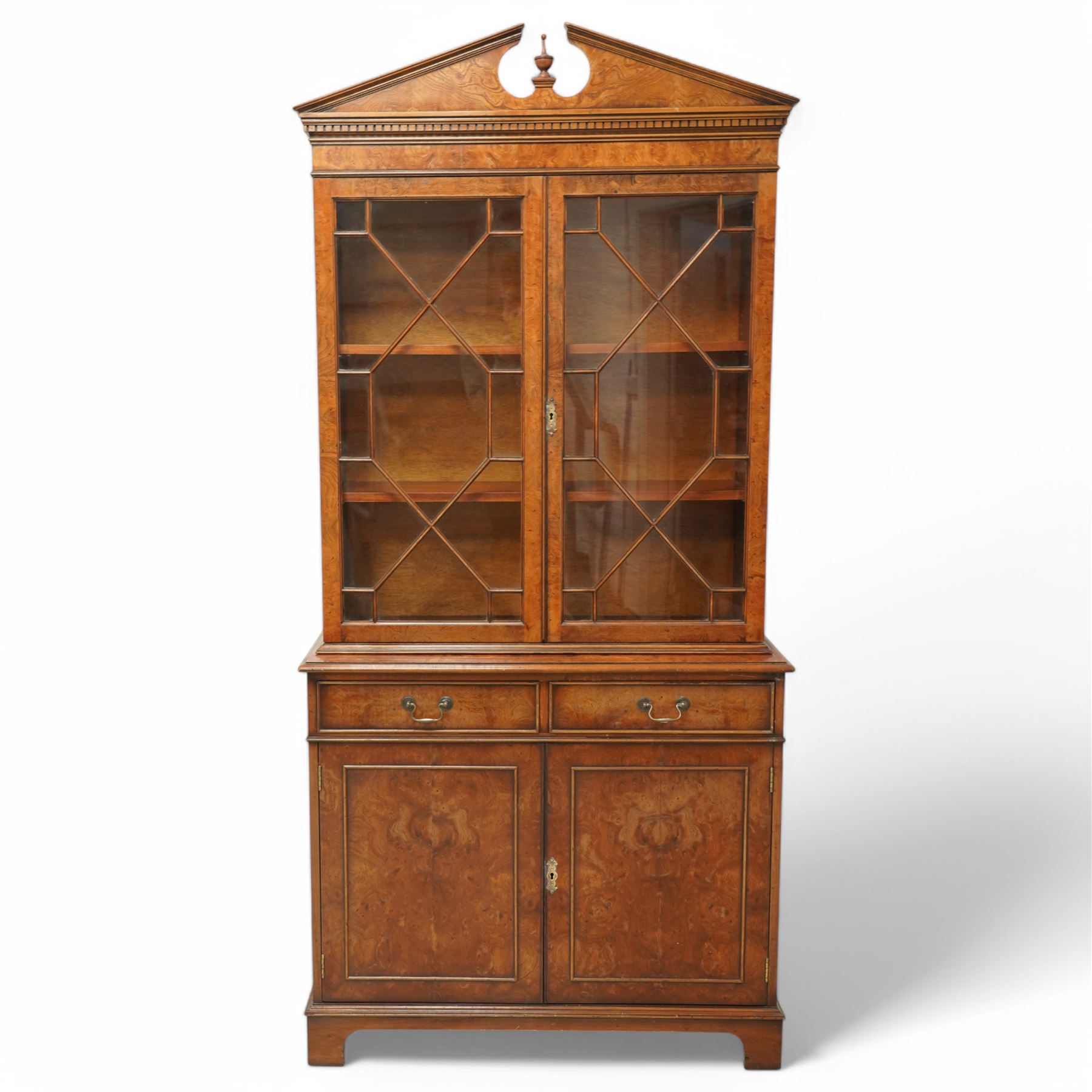 Georgian design Pollard -Oak bookcase cabinet over cupboard with panelled cupboards and two drawers, arched pediment above a dentil frieze and a pair of glazed doors enclosing adjustable shelves, raised on shaped bracket feet