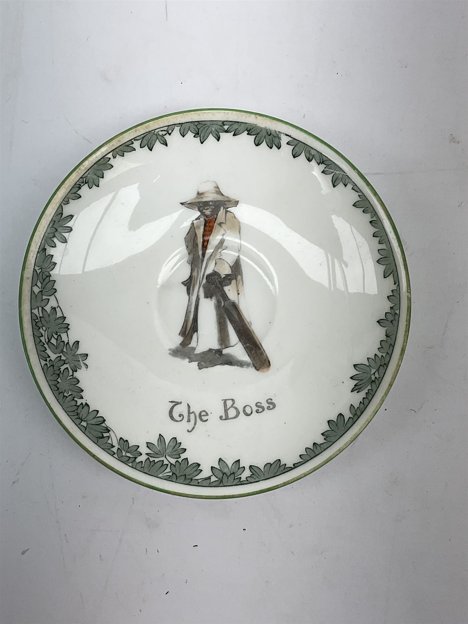 Early 20th century Royal Doulton teacup and saucer, from the series 'The All Black Team', the teacup depicting a cricketer entitled 'Good for fifty', the saucer depicting a cricketer stood in a long coat and wide brimmed hat, entitled 'The Boss', both with printed mark beneath, cup H6.5cm