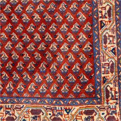 West Persian Saraband (Boteh-Mir) runner madder-red field densely decorated with repeating boteh motifs, arranged in diagonal rows enclosed by a geometric border of stylized motifs, between multiple guard stripes, cotton fringe ends  