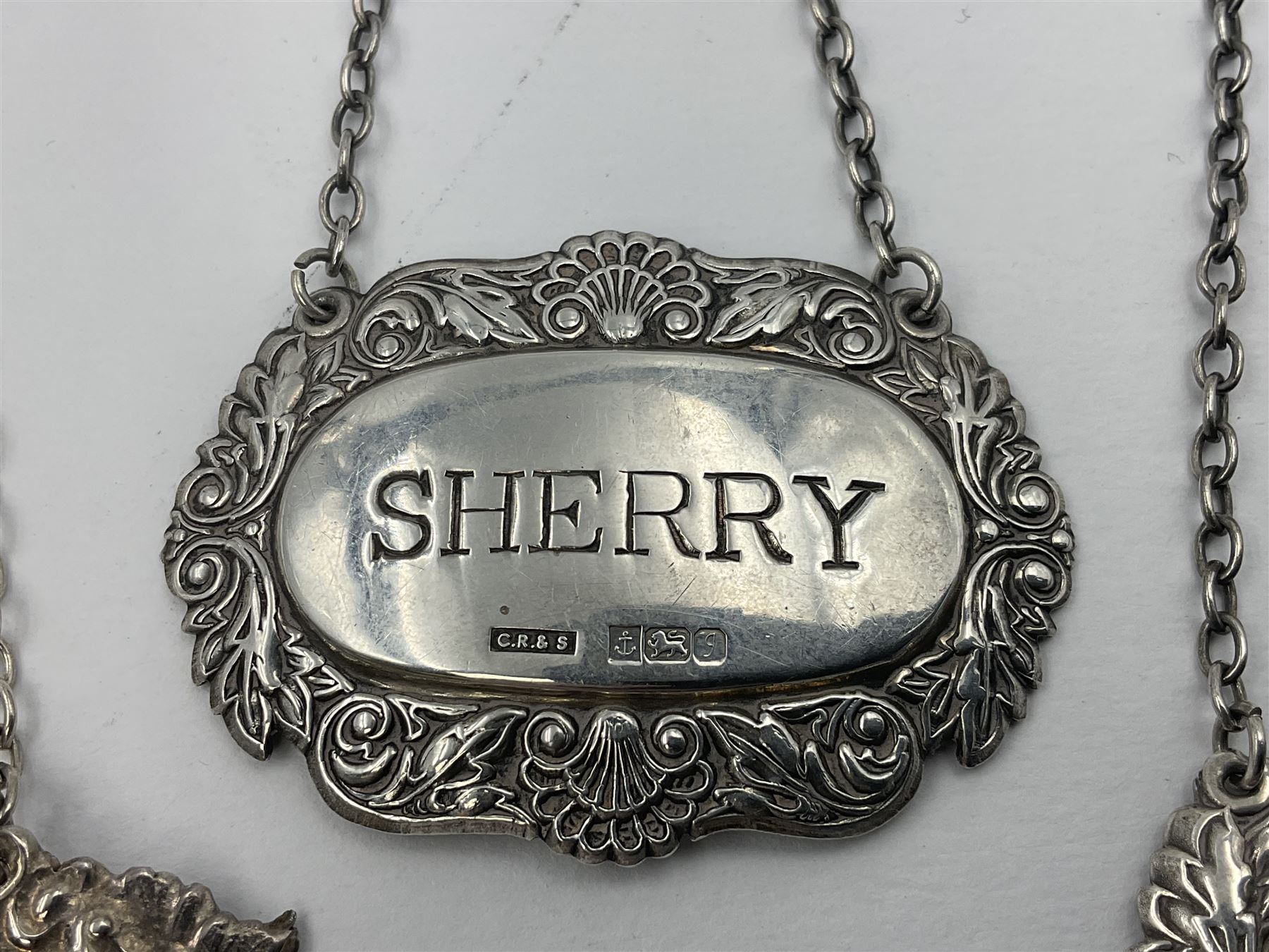 Five modern silver decanter labels, to include three similar Sherry and Brandy examples embossed with scrolls, two hallmarked C Robathan & Son, Birmingham 1989, and one hallmarked Laurence R Watson & Co, Birmingham 1987, together with a scotch example, hallmarked A Marston & Co, Birmingham 1970, and a larger sherry example, embossed with fruiting vines, hallmarked A Marston & Co, Birmingham 1993