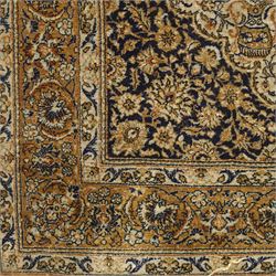Persian Kashan design silk and wool blended rug, with a central medallion incorporating vases and scrolling floral motifs, set against a dark blue and ivory ground within a patterned border, some fraying to end fringes