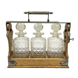 Betjemann patent silver plate mounted oak tantalus, containing three square sided cut glass decanters, complete with key, H30cm