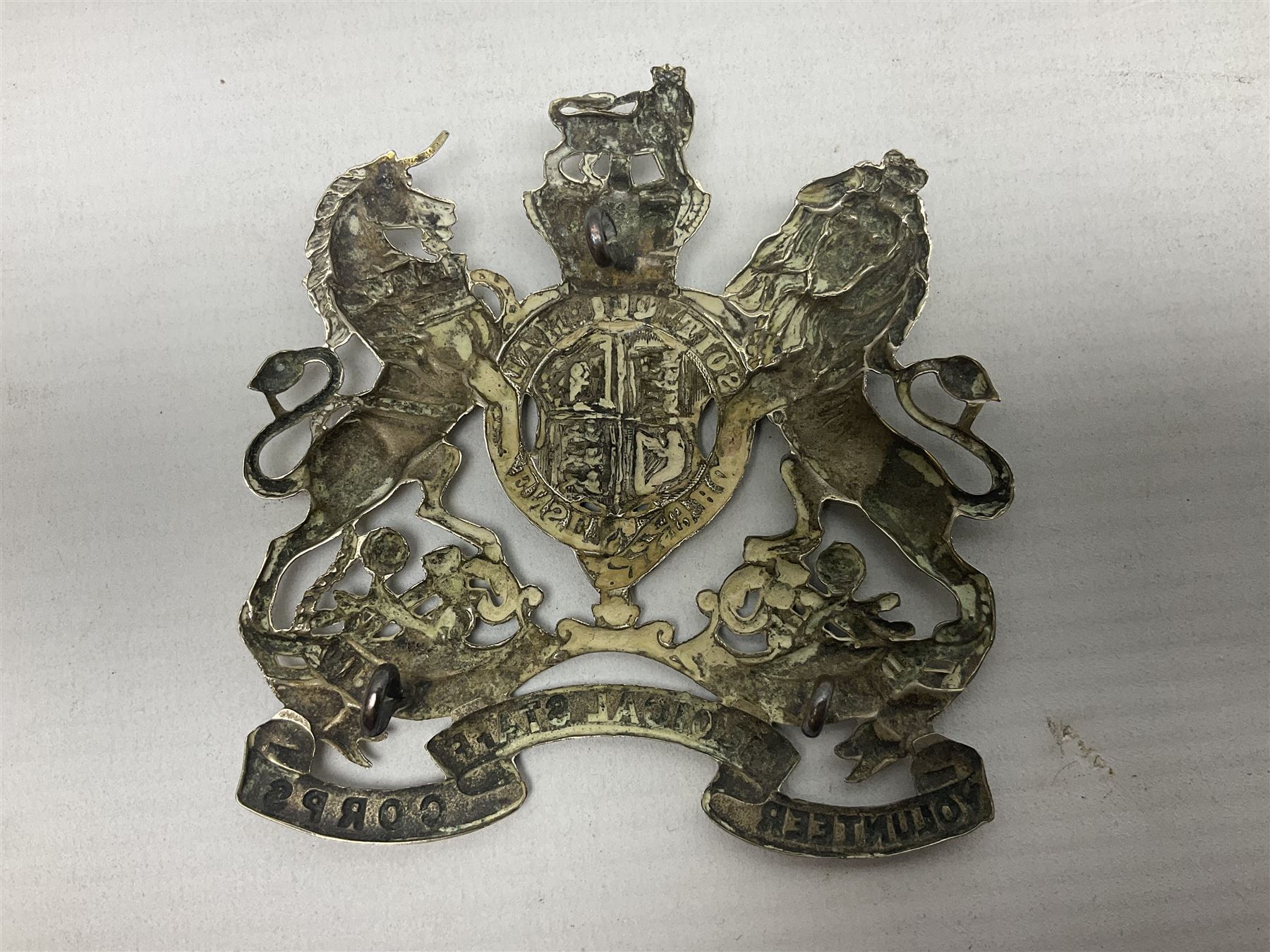 Victorian Volunteer Medical Staff Corps white metal helmet plate in the form of Victorian crowned Royal Arms with three part lower scroll for “VOLUNTEER MEDICAL STAFF CORPS”; three lug fittings to the reverse L8.5cm