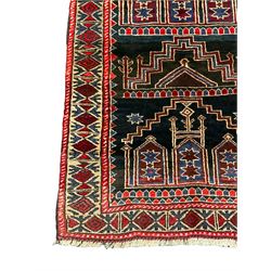 Baluchi dark indigo and crimson ground rug, decorated with cityscape within geometric border 